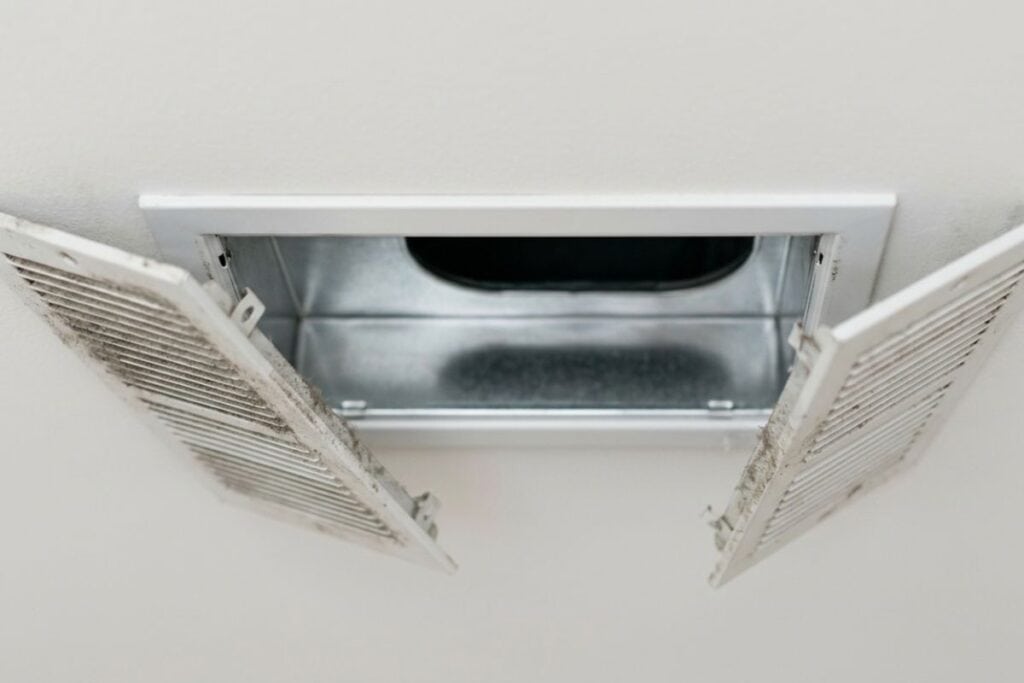 Professional HVAC technician cleaning a residential air duct system with negative-pressure equipment in a Tulsa, OK home